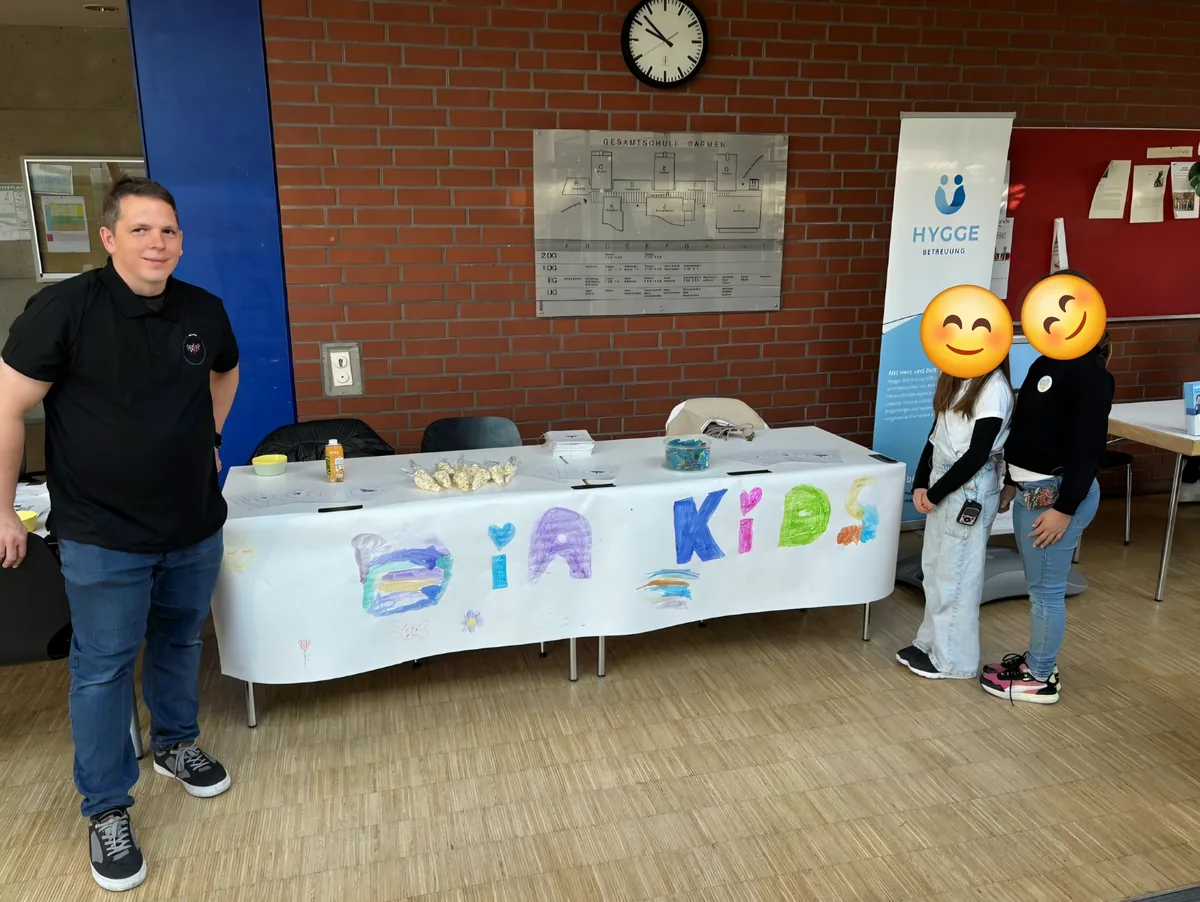 Pascal Wimmershoff am Stand der Dia-Kids mit selbstgemaltem Banner, daneben zwei Kinder, deren Gesichter mit Emojis verdeckt sind